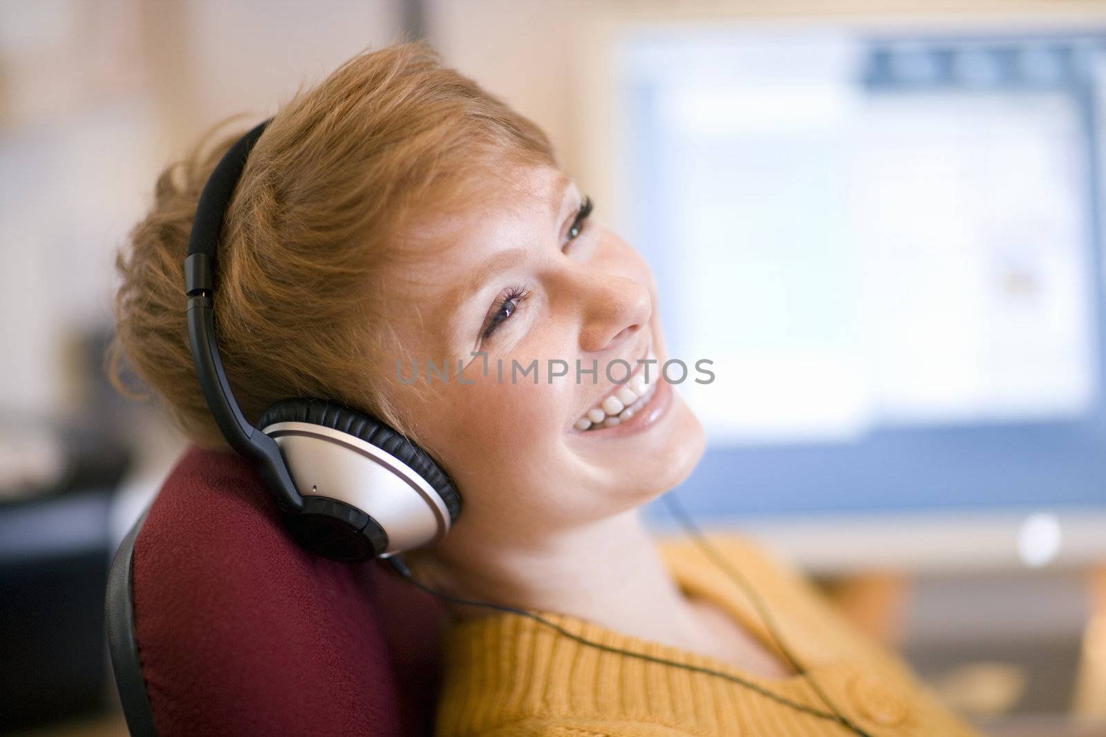 Young laughing woman relaxing in chair listening to headphones