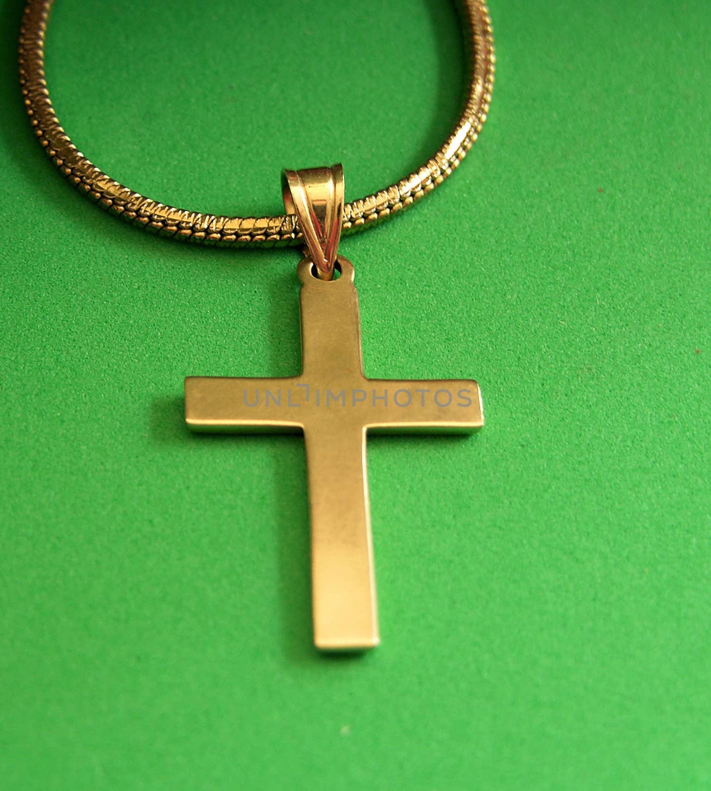          A gold cross seen up close on a green backgound