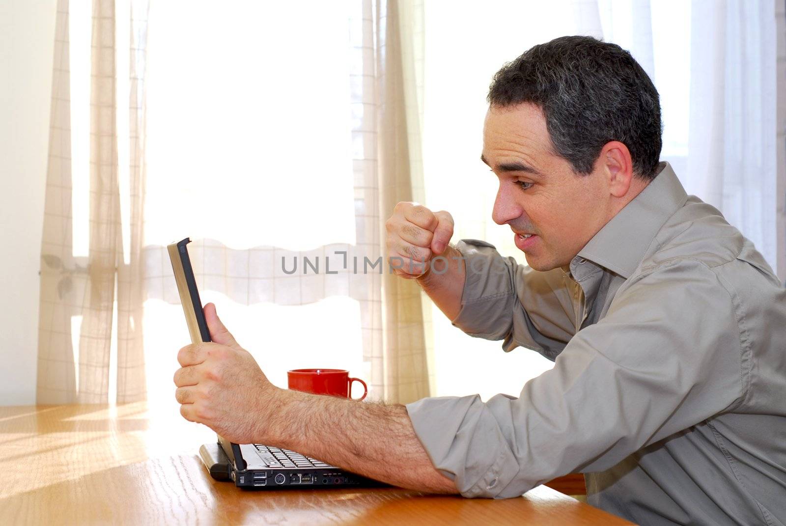 Man sitting at a desk punching his computer in frustration