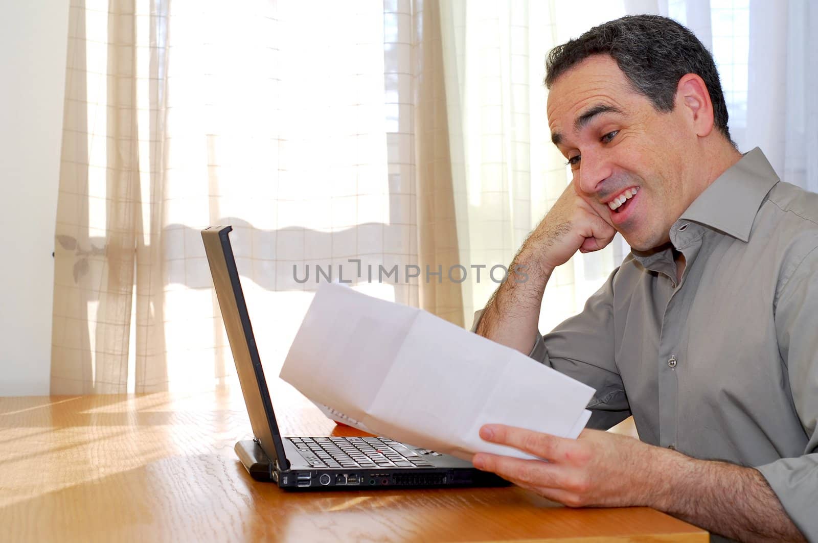 Man sitting at a desk looking at bills and smiling