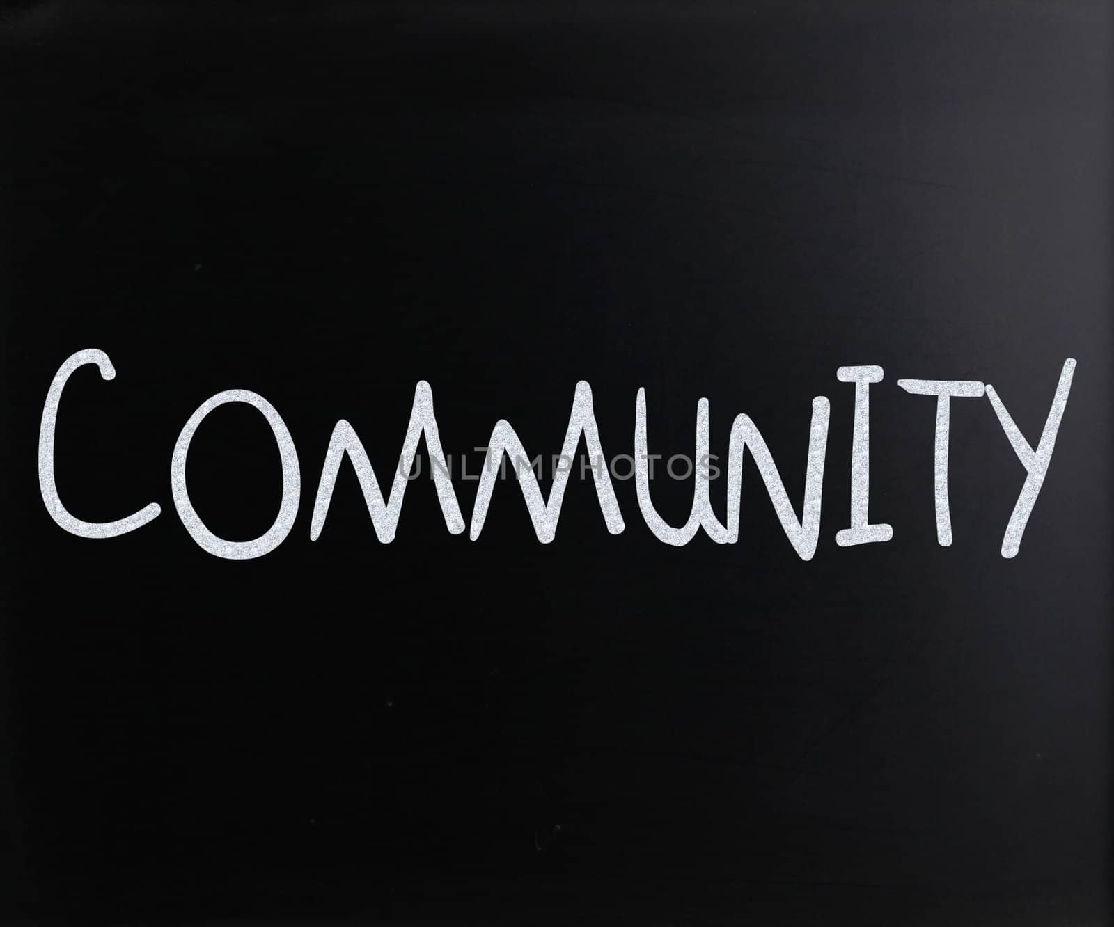 "Community" handwritten with white chalk on a blackboard