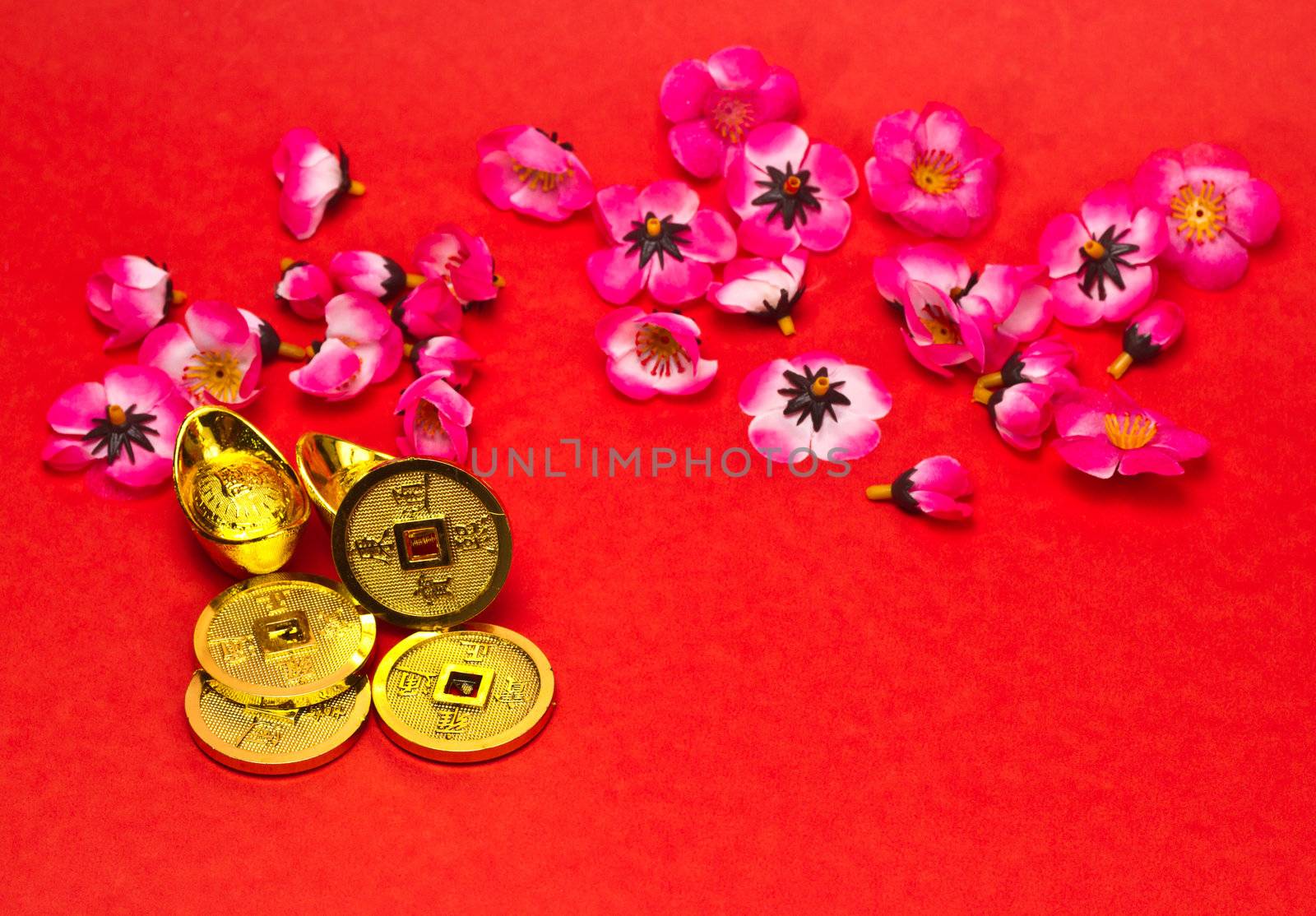 Golden nuggets and emperors coins with cherry plum blossoms on red surface for Chinese New Year
