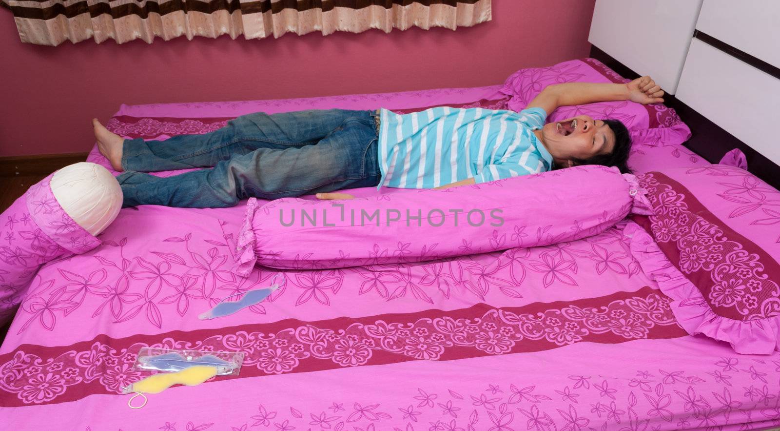 Asian man yawns on the bed on World Sleeping Day.