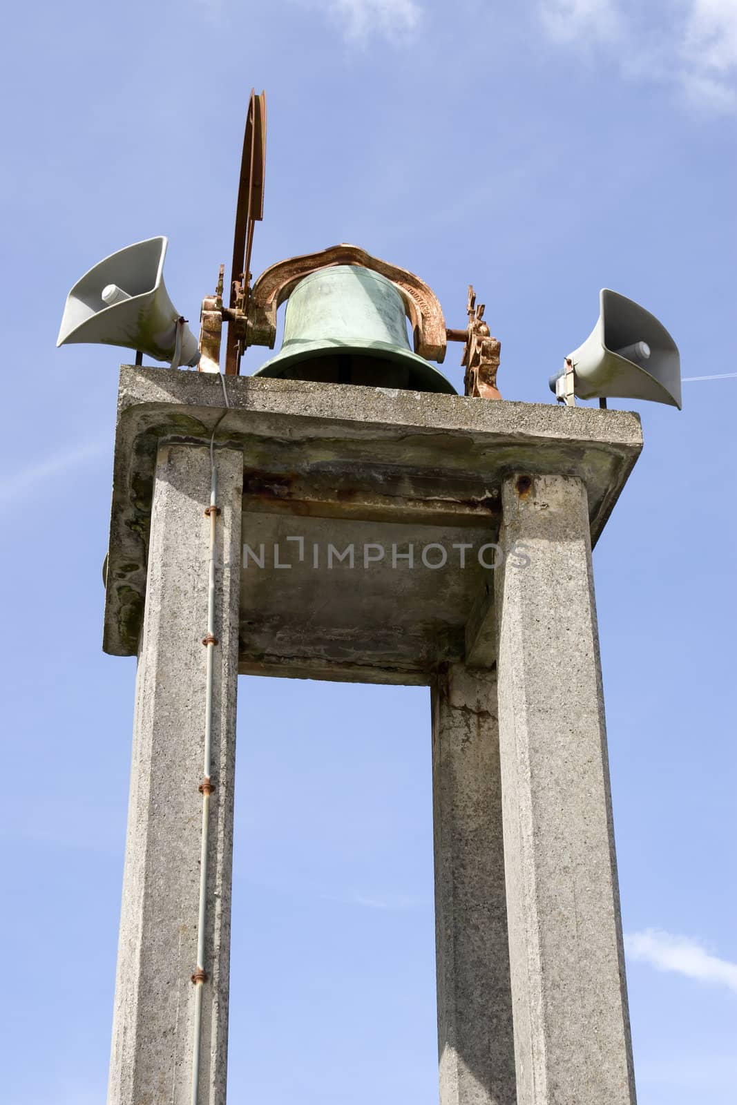 an old church bell against a blue sky by morrbyte