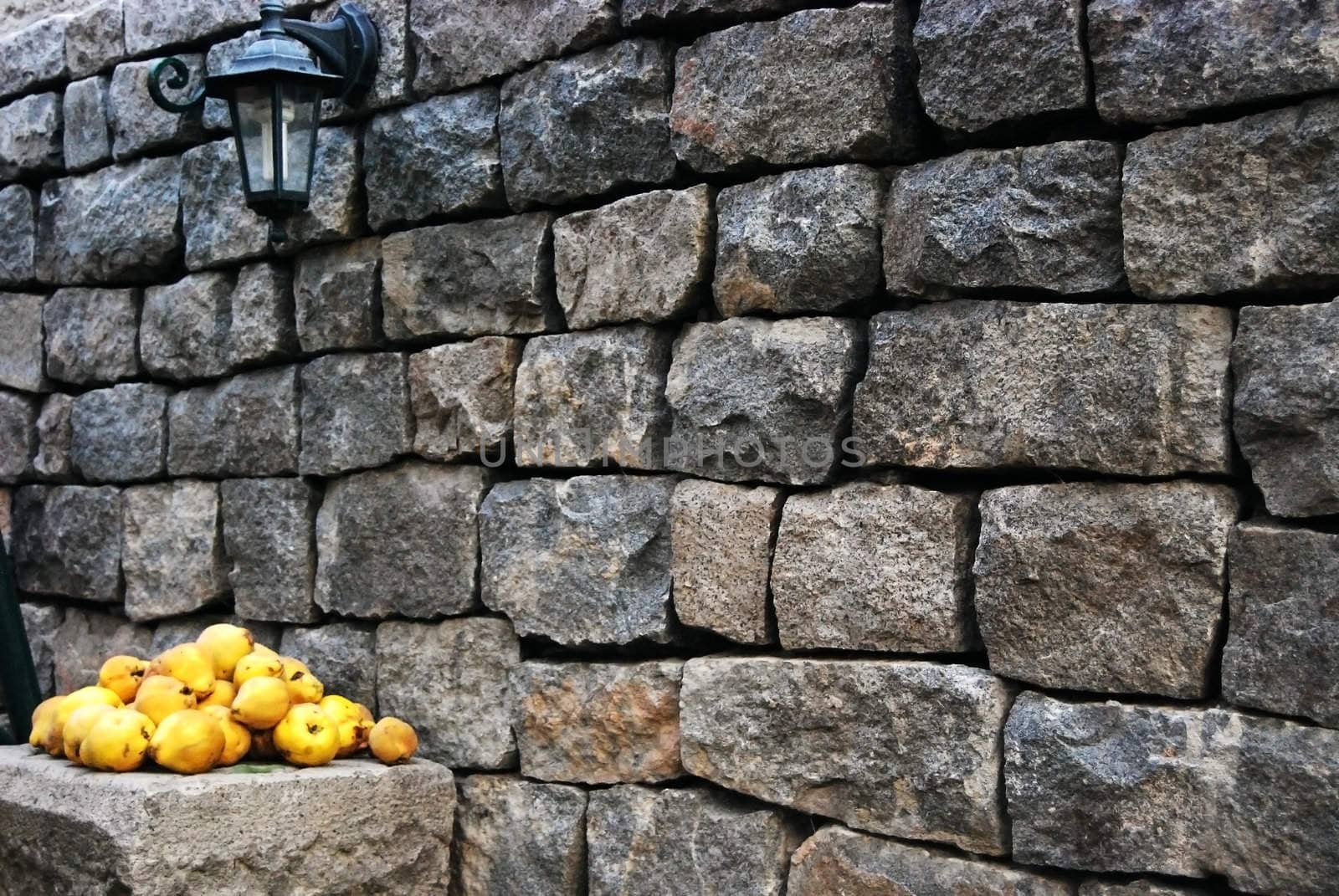 Granite stone wall and heap of yellow quinces
