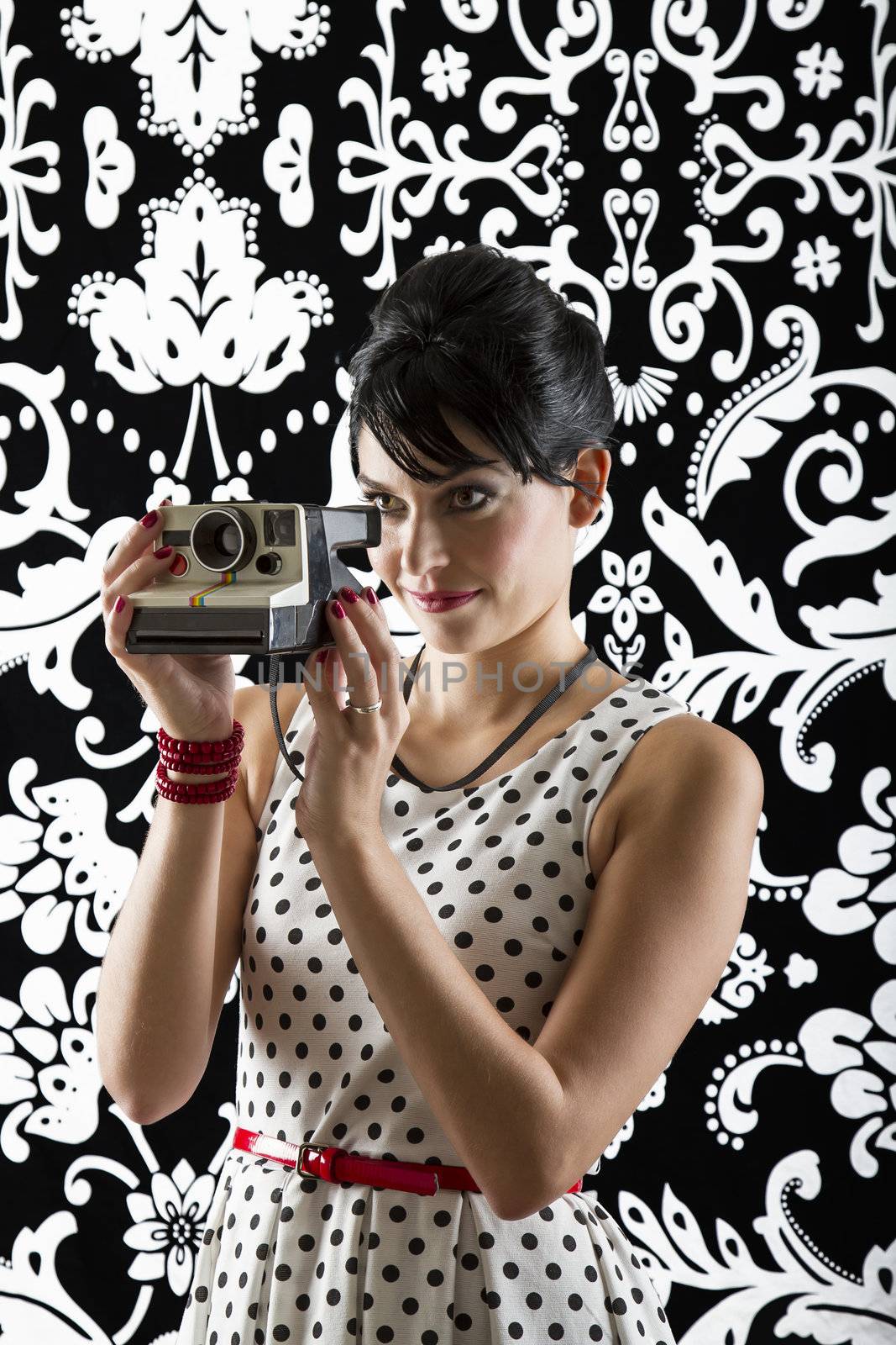 young woman is stylist 60's inspired clothing, holding a camera