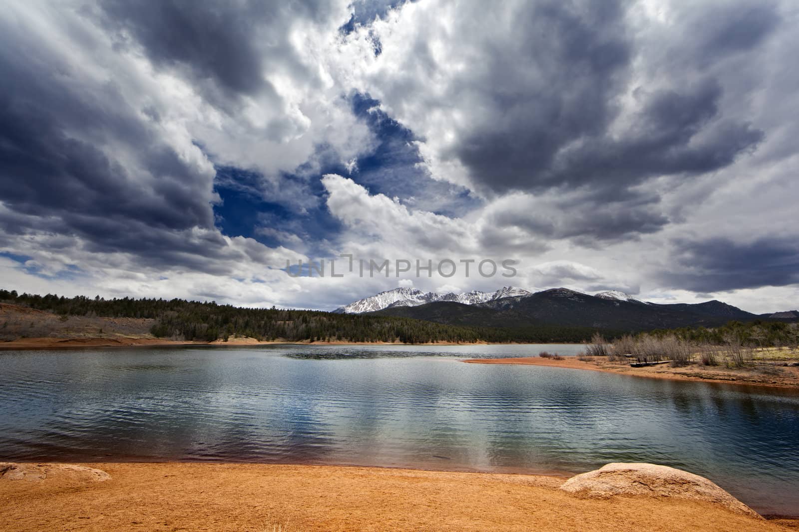 A wide angle shot of a lake in front of the Rocky Mountains.