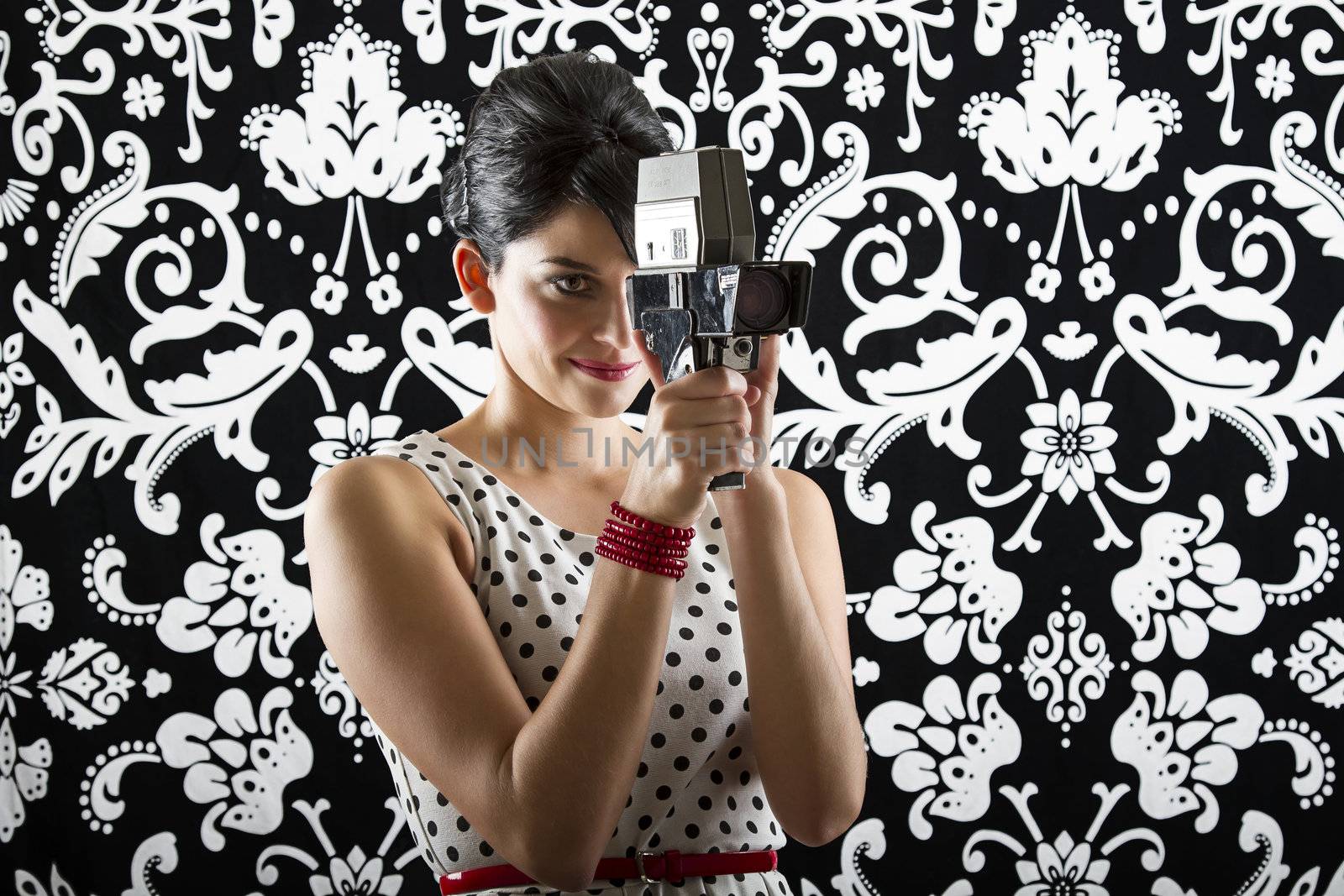 young woman is stylist 60's inspired clothing, holding a super 8 mm to her eye