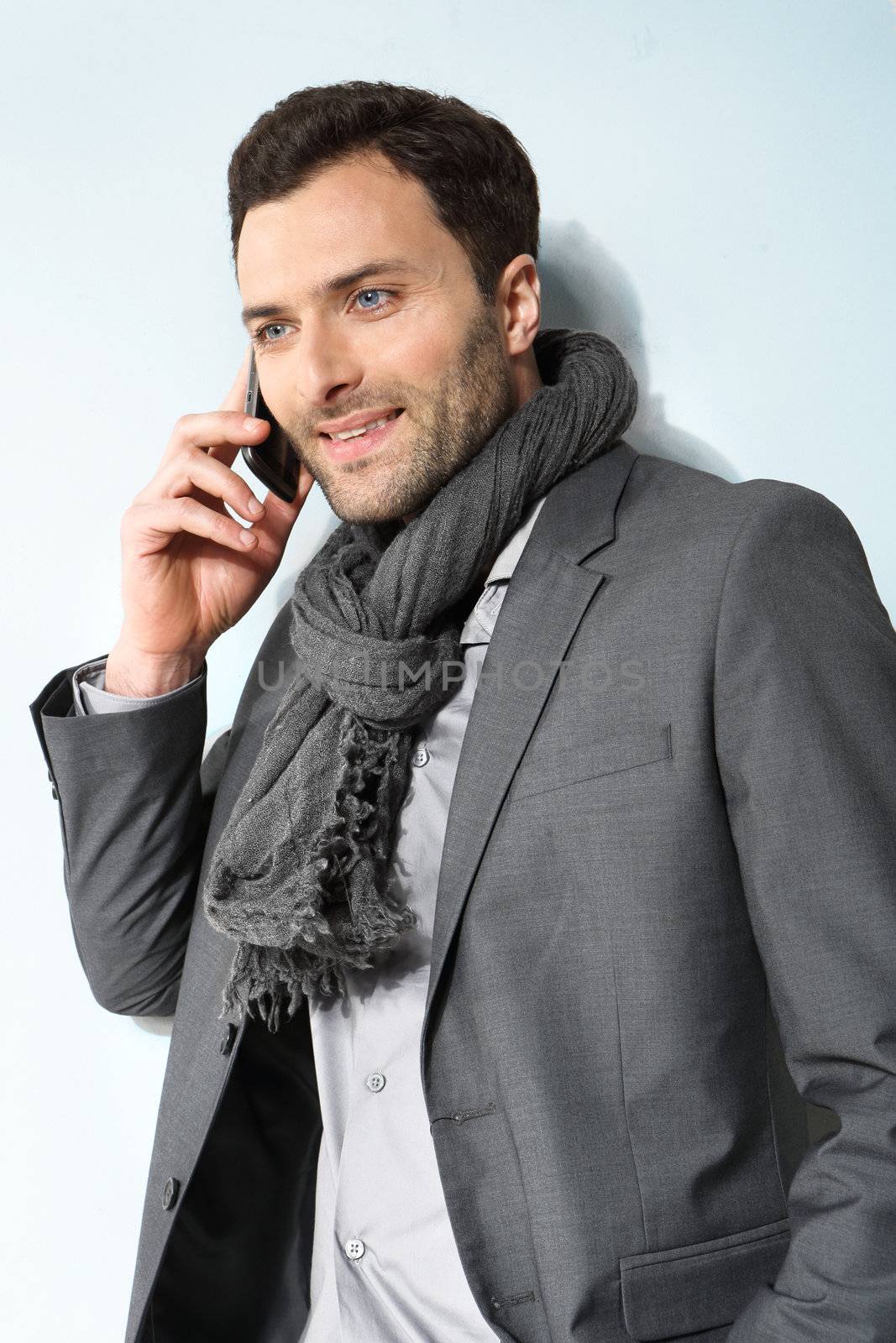 Young businessman using cell phone, over grey background