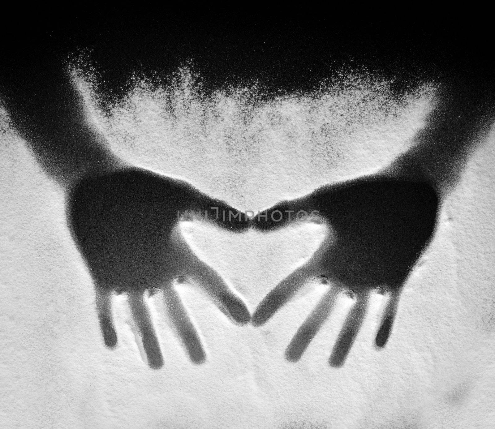 Two hands creating a heart on flour