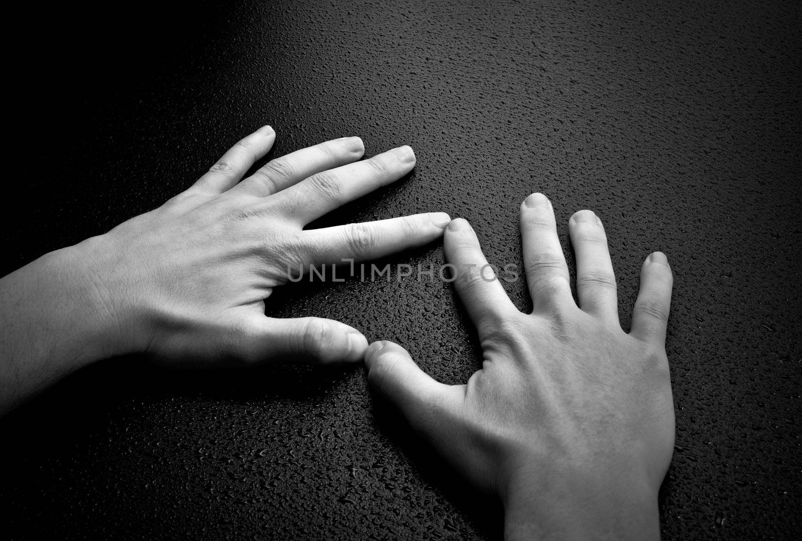 Two hands creating a heart shape on wet wood background