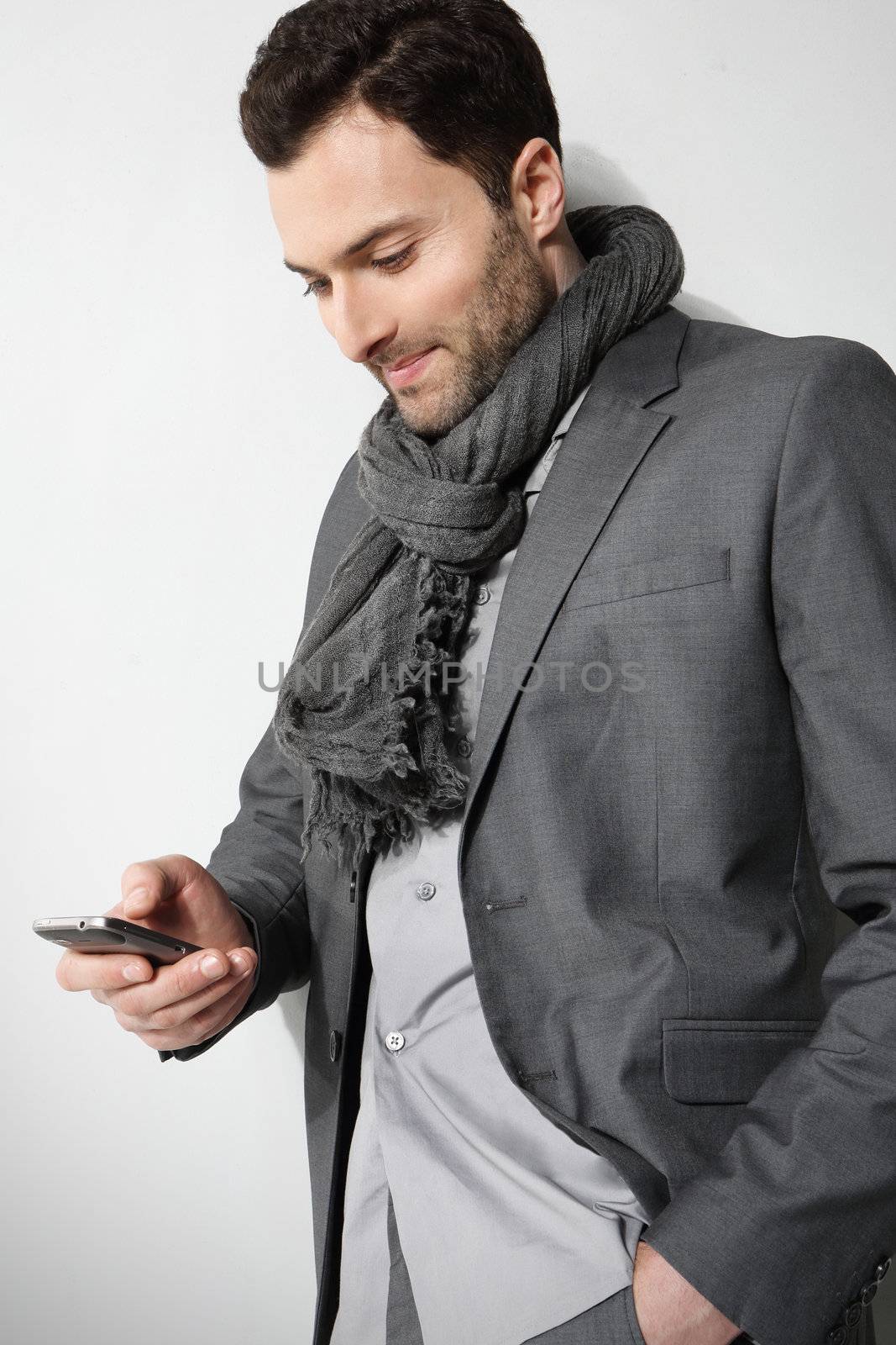 Young businessman using cell phone, over grey background