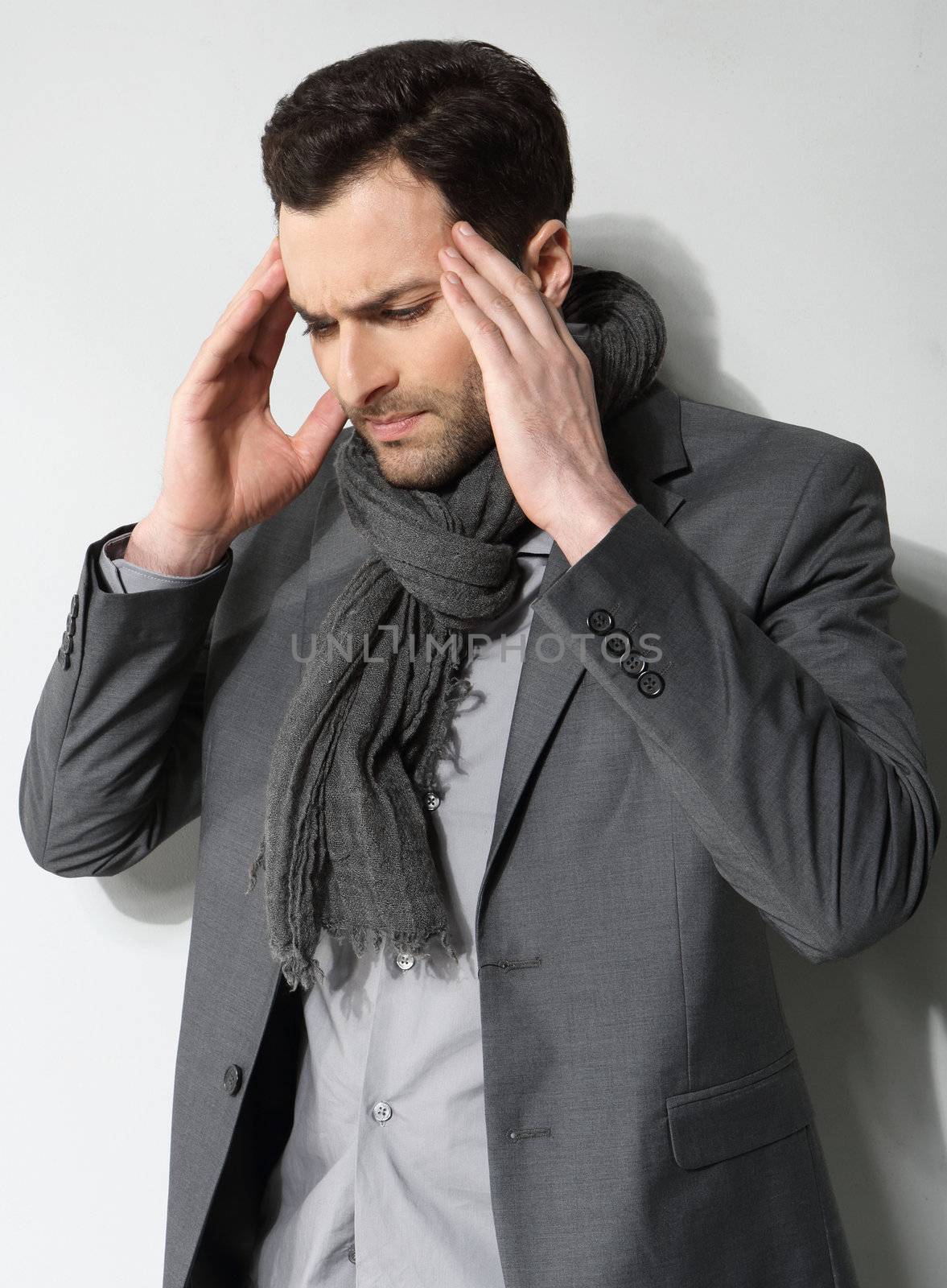 Stressed businessman with a headache on a gray background