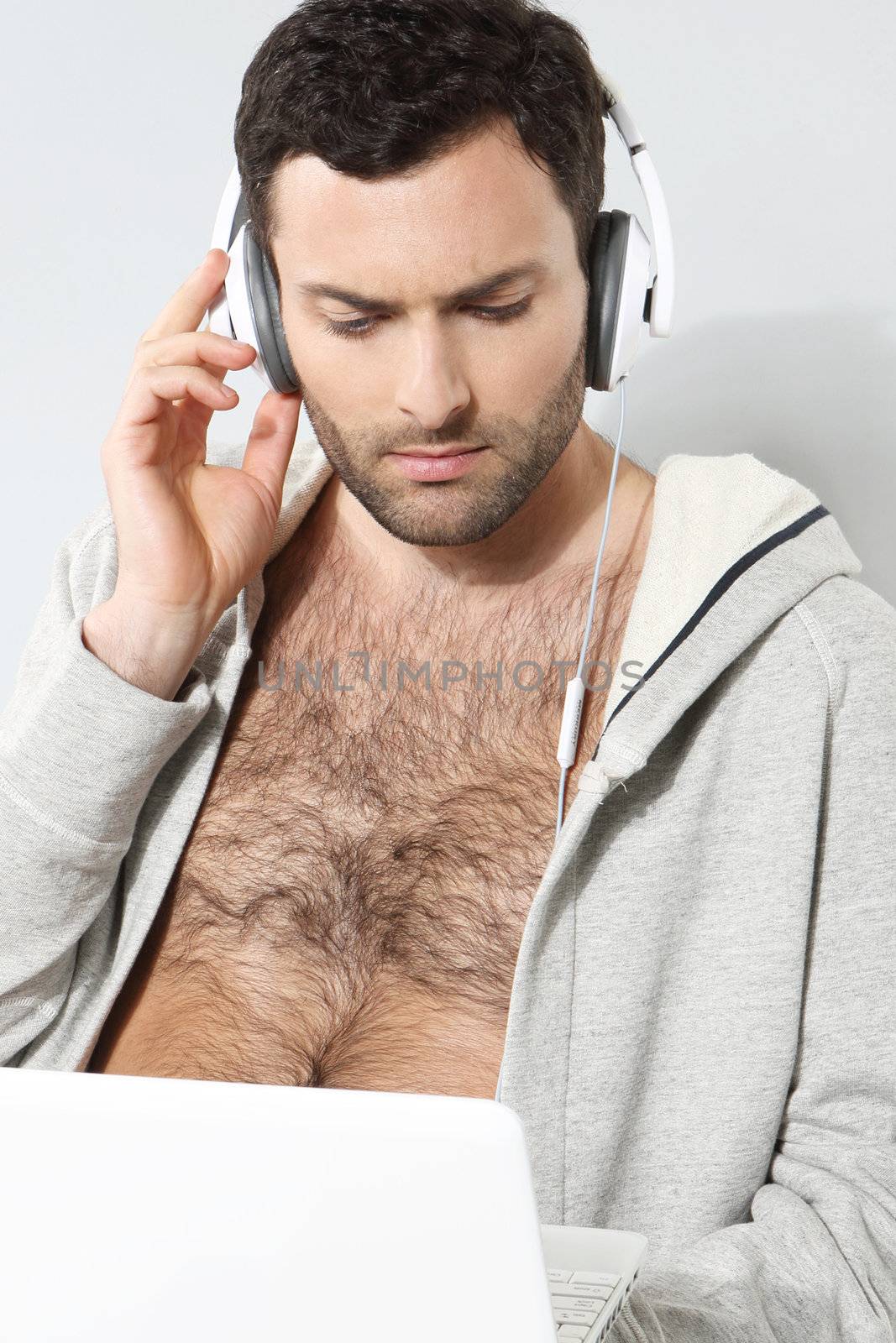 Stylish man listening to music on a gray background by robert_przybysz