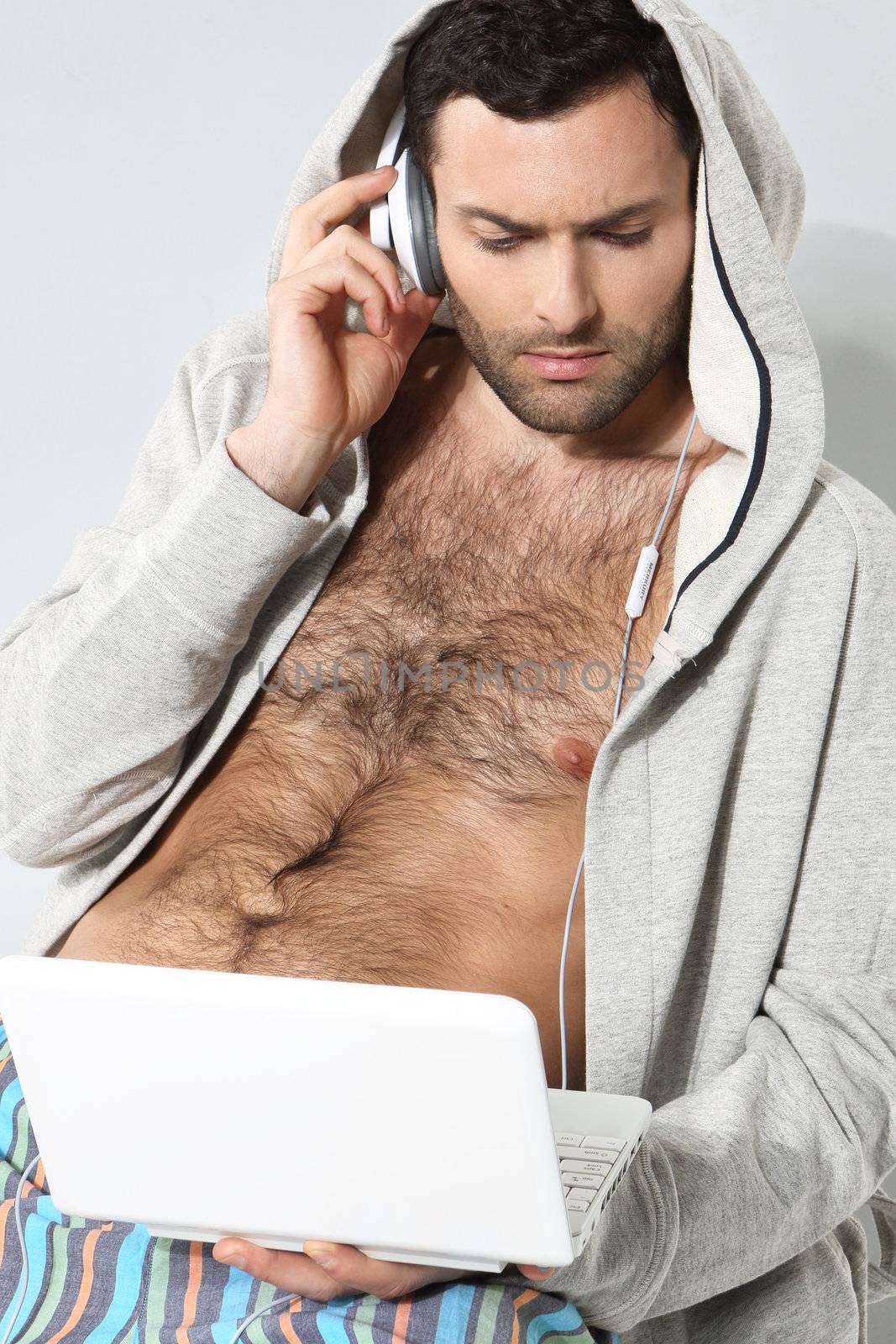 Stylish man listening to music on a gray background by robert_przybysz