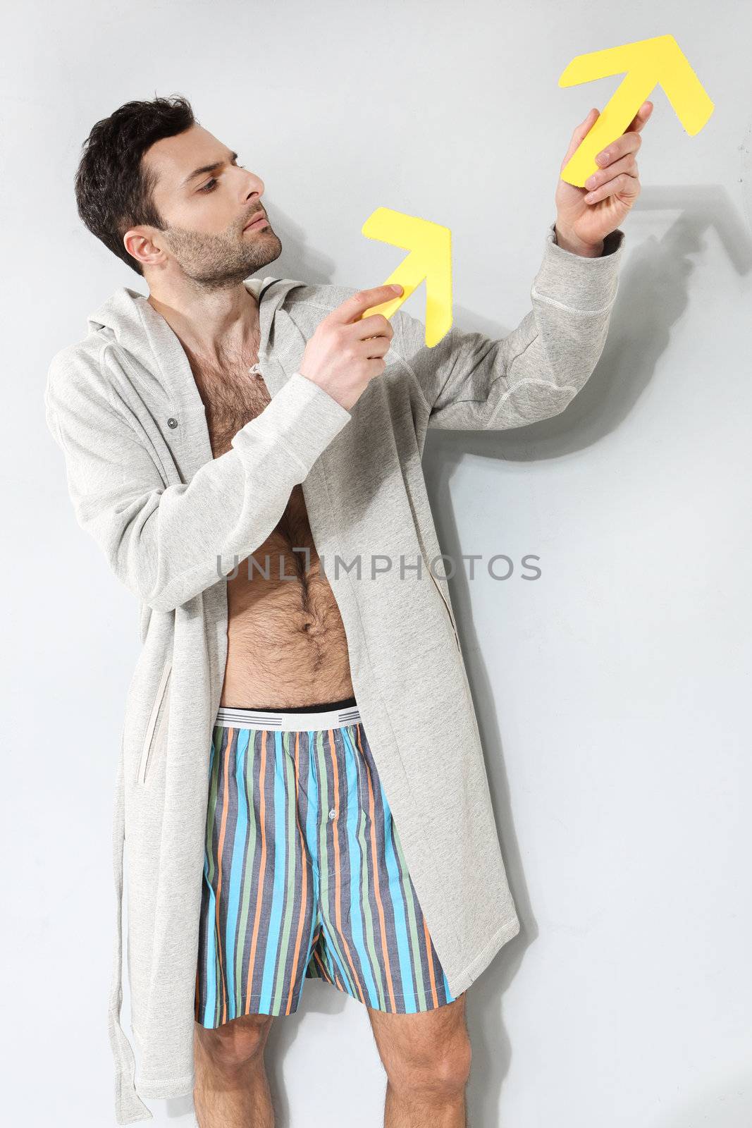 Man holding yellow arrows on a gray background by robert_przybysz