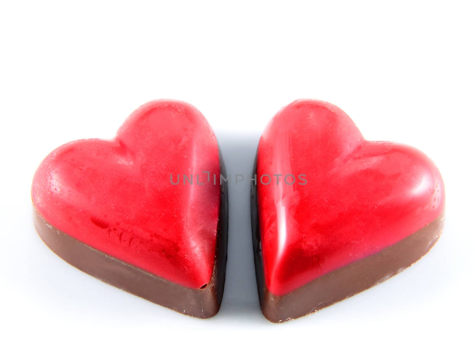two chocolates shaped red heart isolated on white background