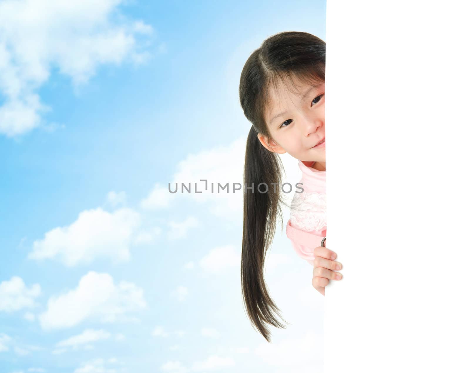 Young Asian girl hiding behind a blank white card in summer day, blue sky as background.