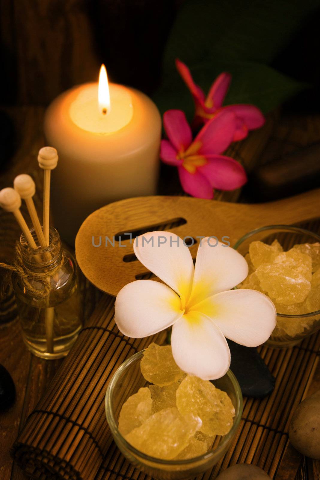 Spa and wellness setting with natural salt, candles and frangipani. Low light dayspa nature set .