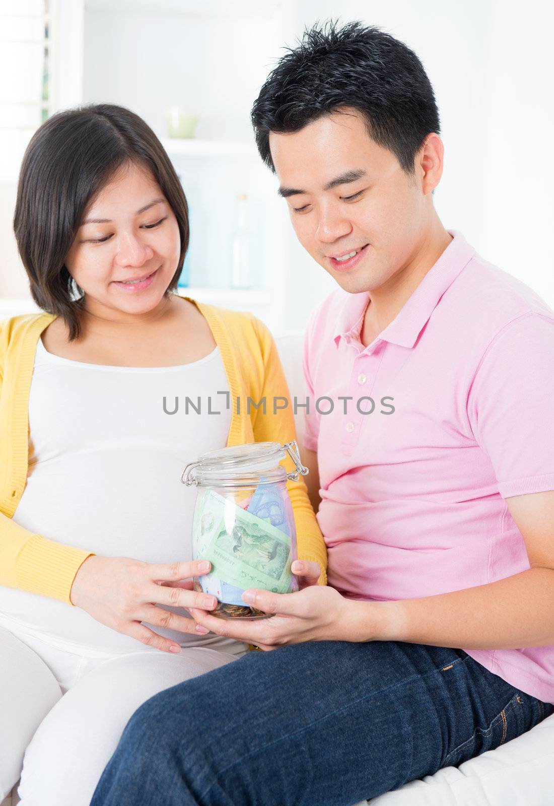 Asian family financial planning concept. Young pregnant couple saving money for future. Living lifestyle at home.