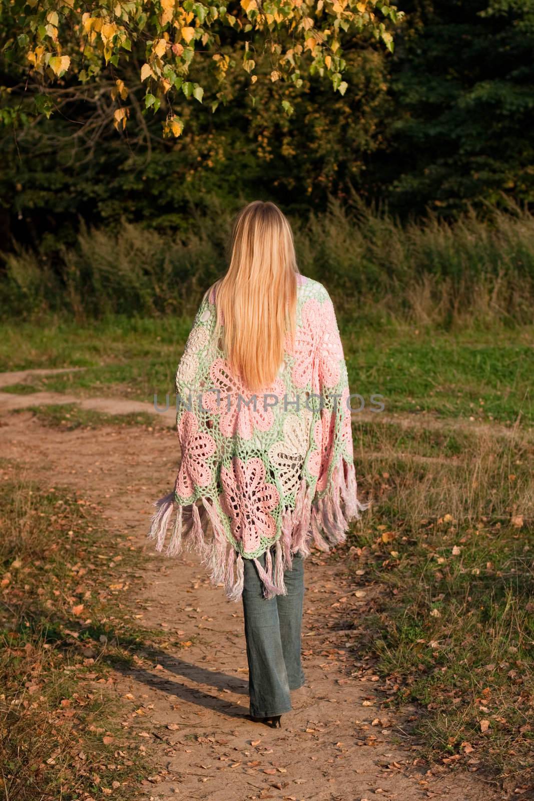 A walking girl in a swal and jeans in a forest
