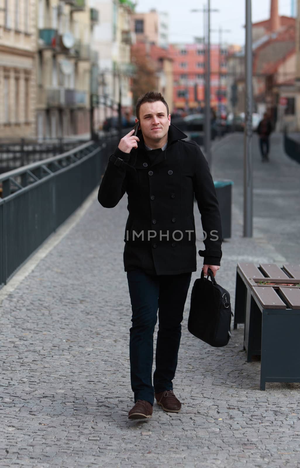 Young casual man on the phone in a small cobbled city street.