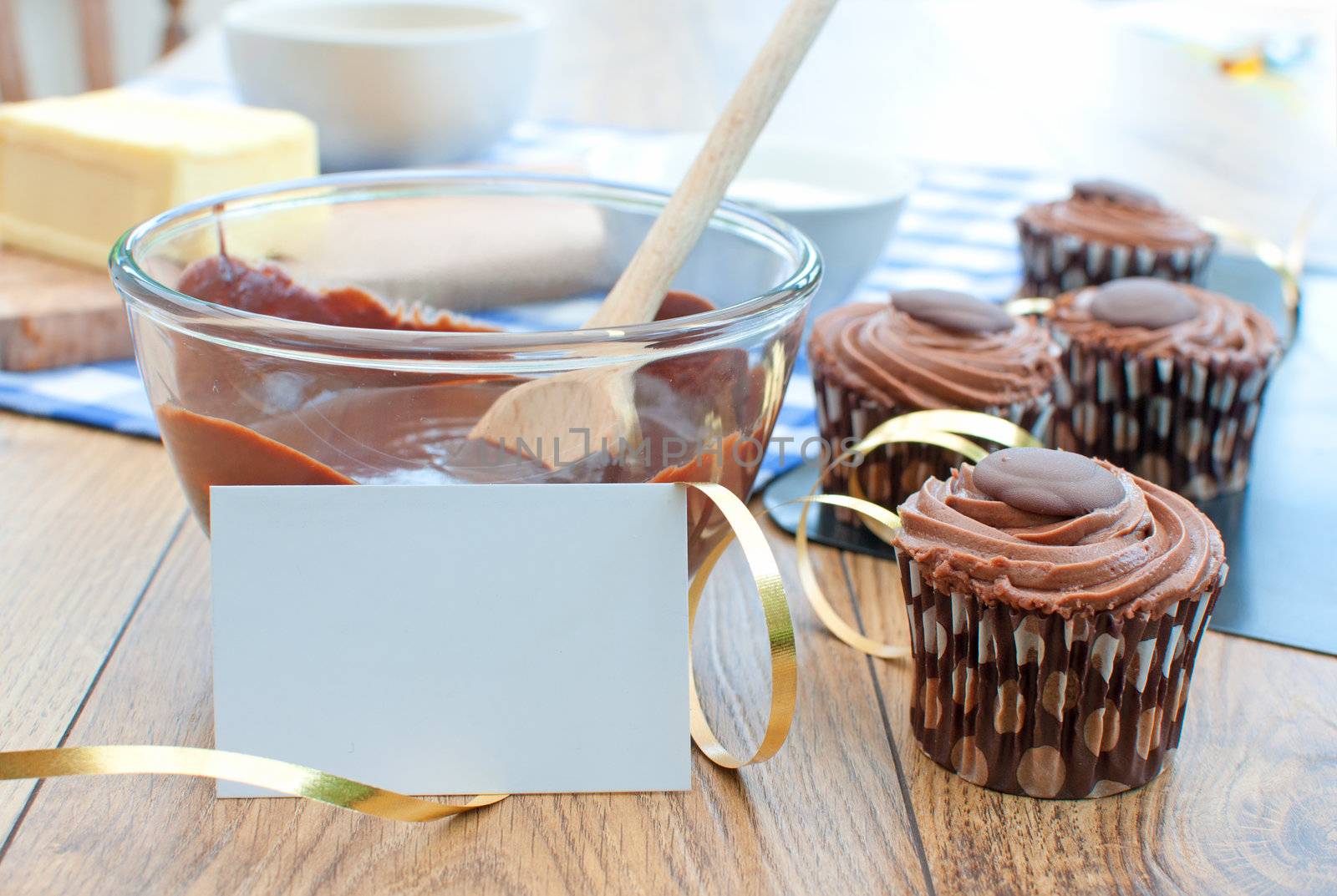 Chocolate cupcakes on a baking tray with a gold ribbon decoration and blank card