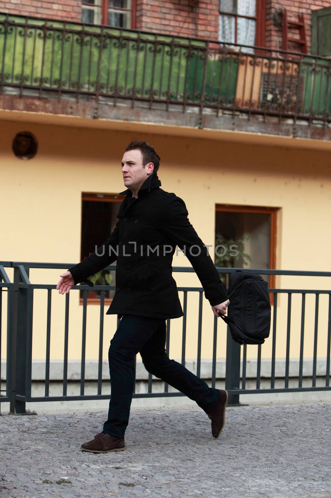 Young casual man in a hurry in a small cobbled city street.