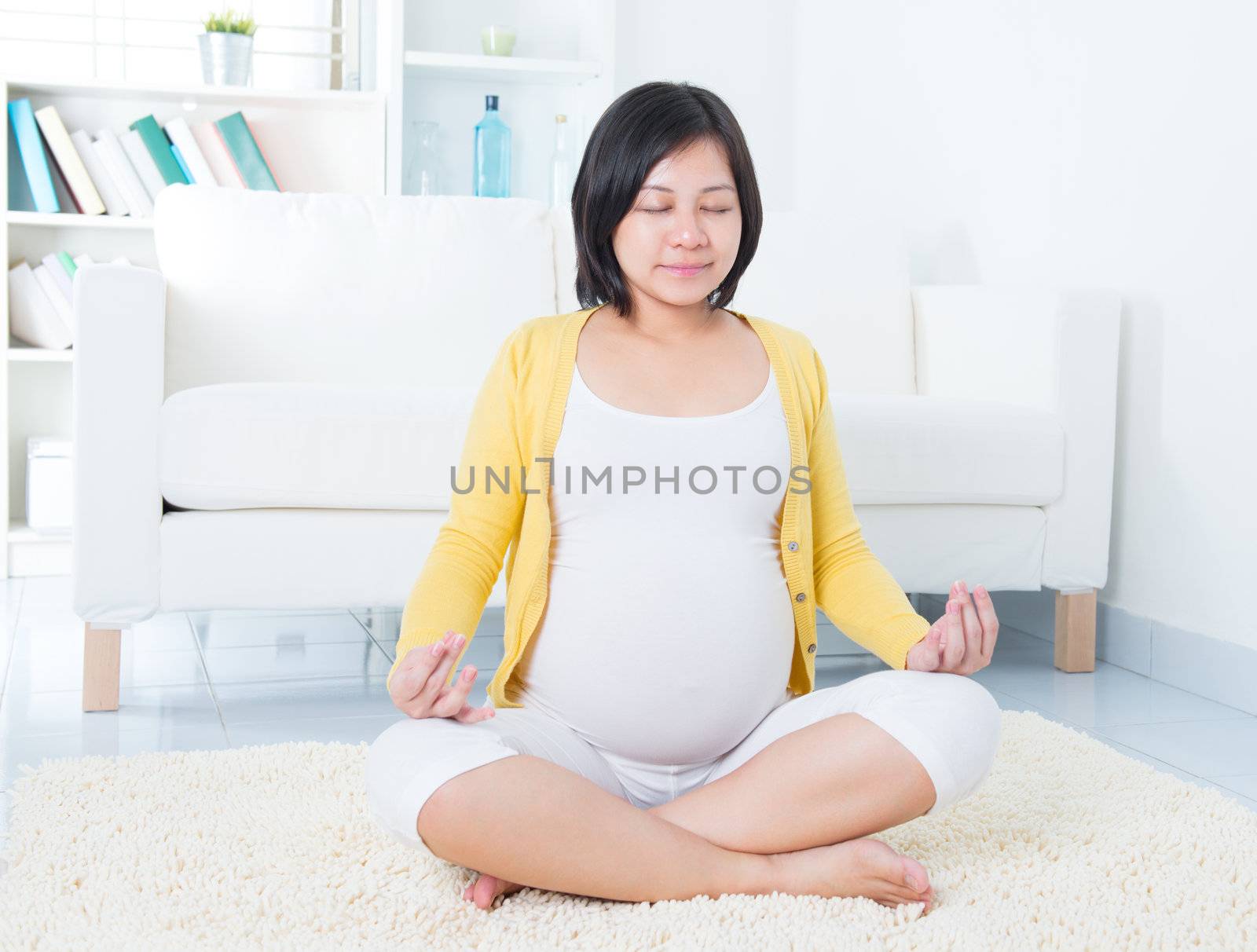 Calm Asian pregnant woman meditating at home.
