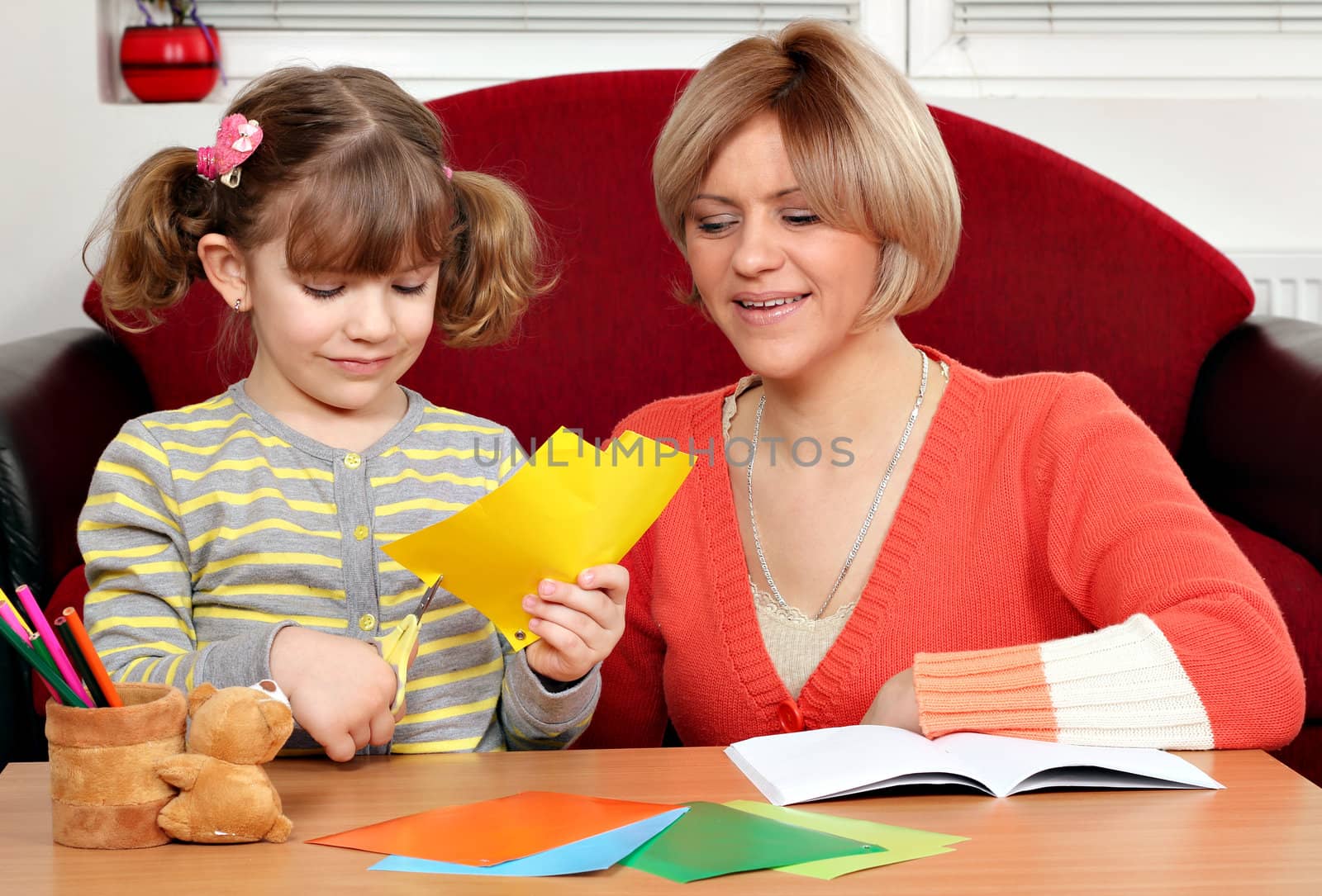 little girl cutting paper with scissors by goce