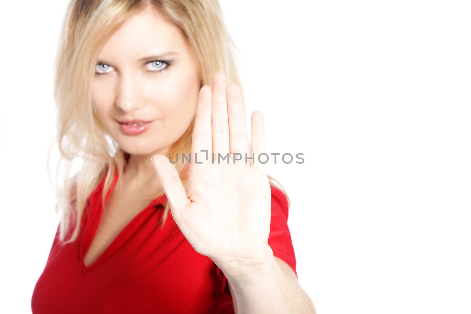 Attractive young woman making a cease and desist gesture with her hand holding her palm up to the camera