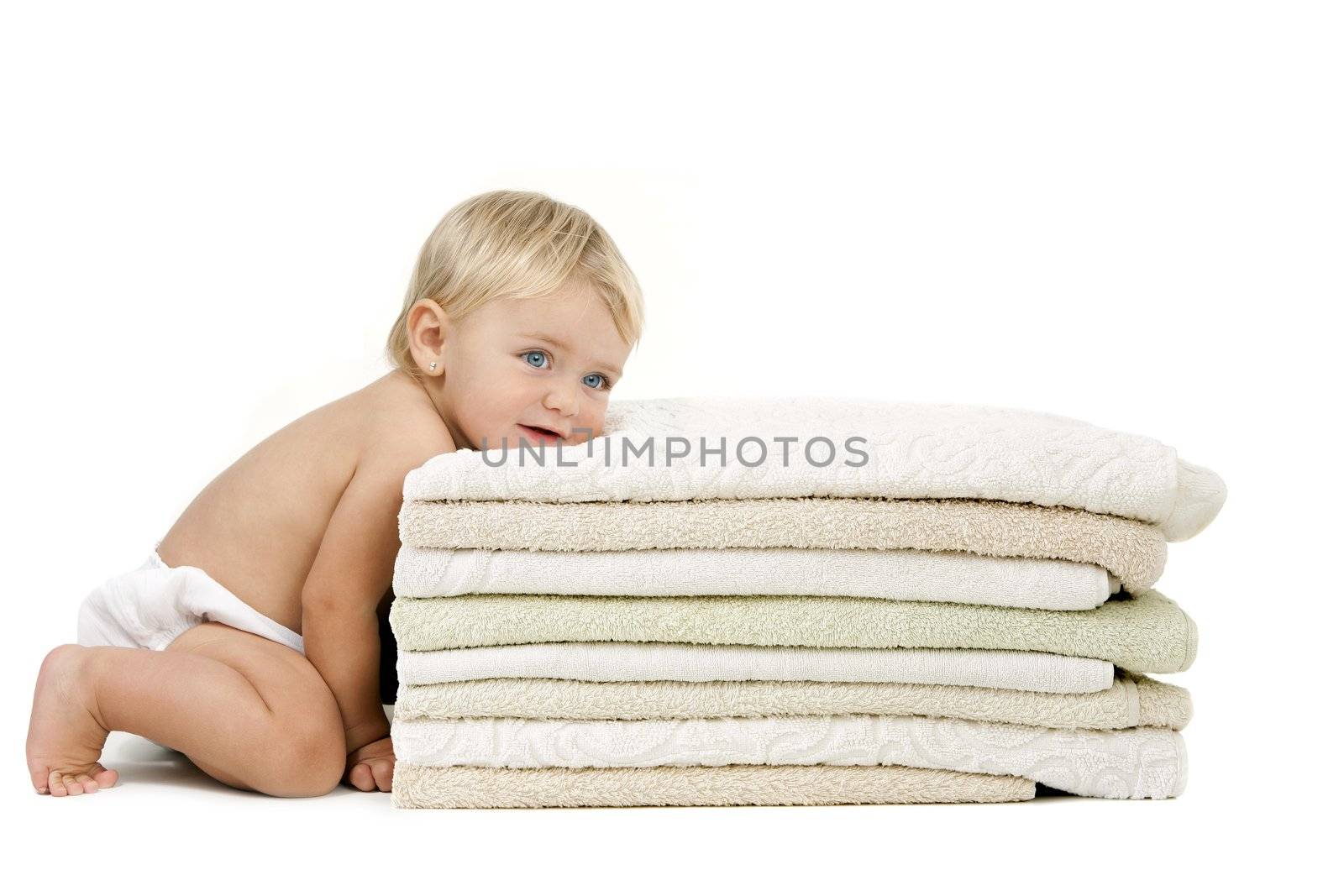 Blue eyed baby girl with relaxed expression resting her head on a pile of towels. Isolated on white background.