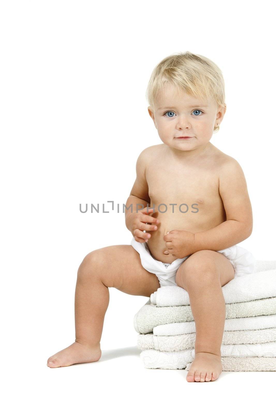 Blue eyed baby girl  sitting on a pile of towels. Isolated on white background.