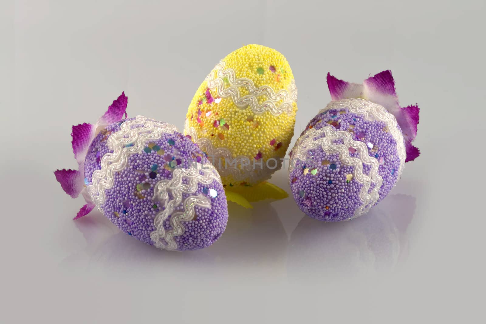 Three eggs decorated in a light grey background