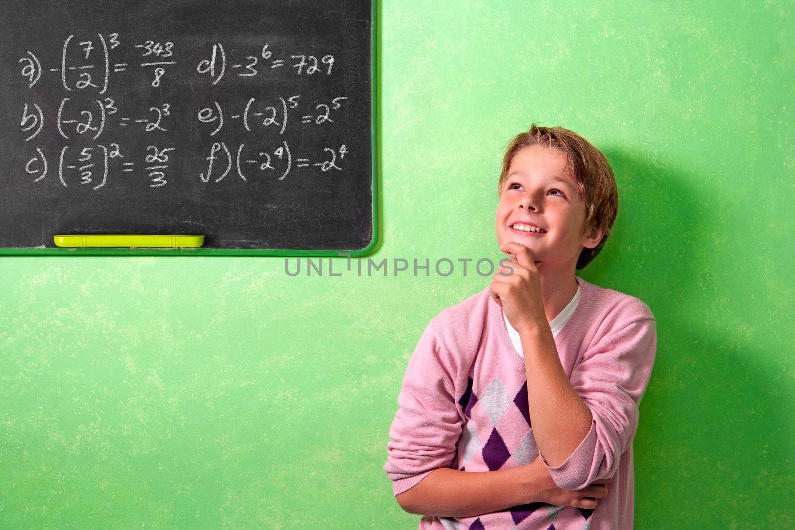 Young attractive boy standing in front of blackboard with wondering face expression.