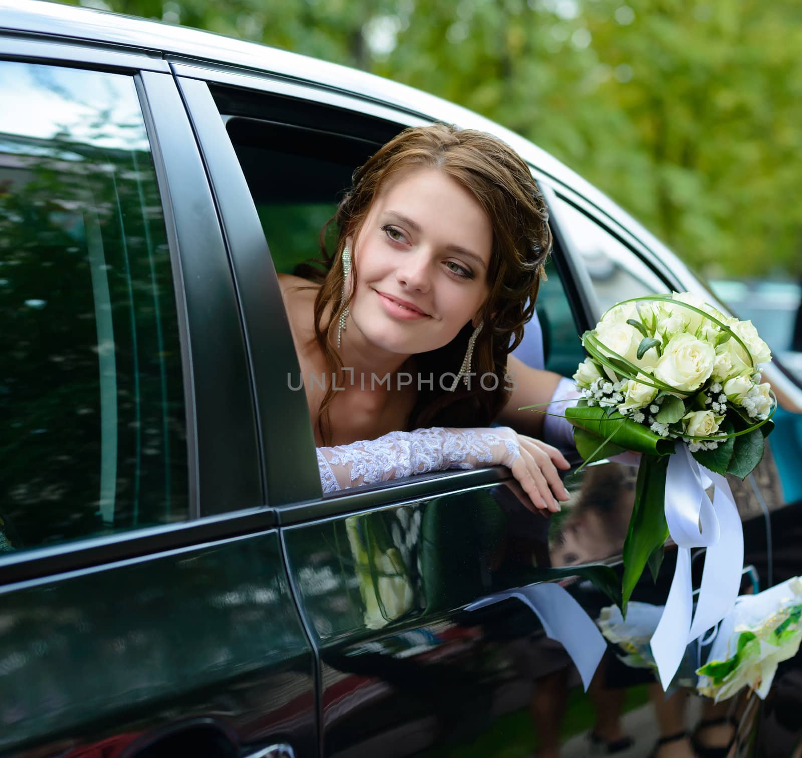 portrait of a pretty smiling bride in a car window