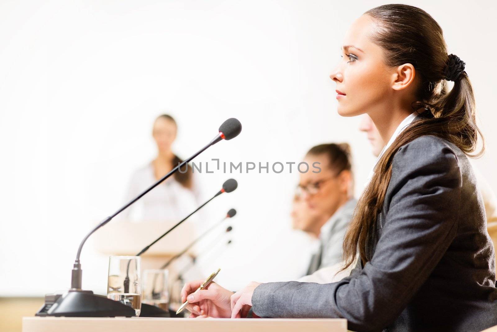 businessmen talking at the conference, sitting at the table, on the table microphones and documemts