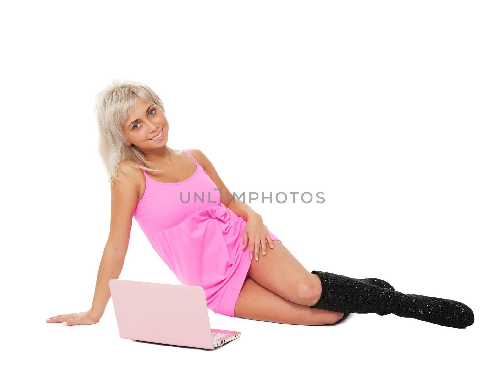 Beautiful blonde in a pink dress is in a laptop in black boots.