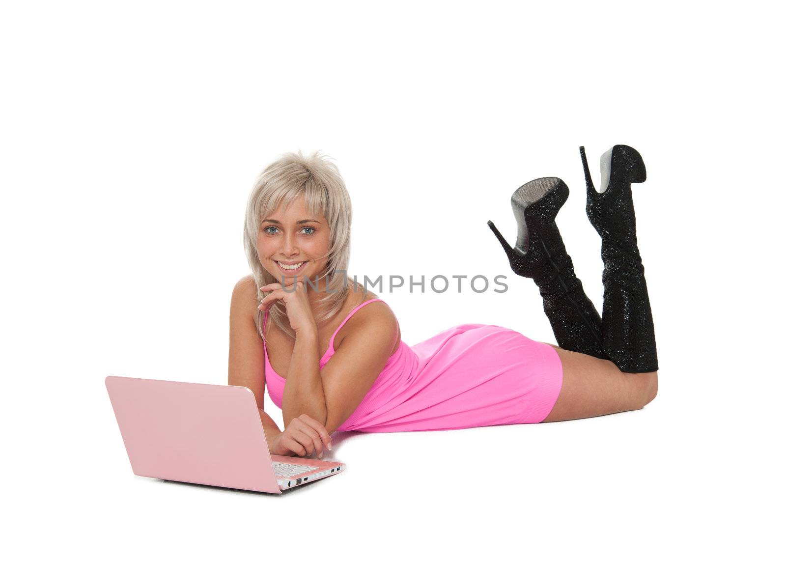 Beautiful blonde in a pink dress is in a laptop in black boots.