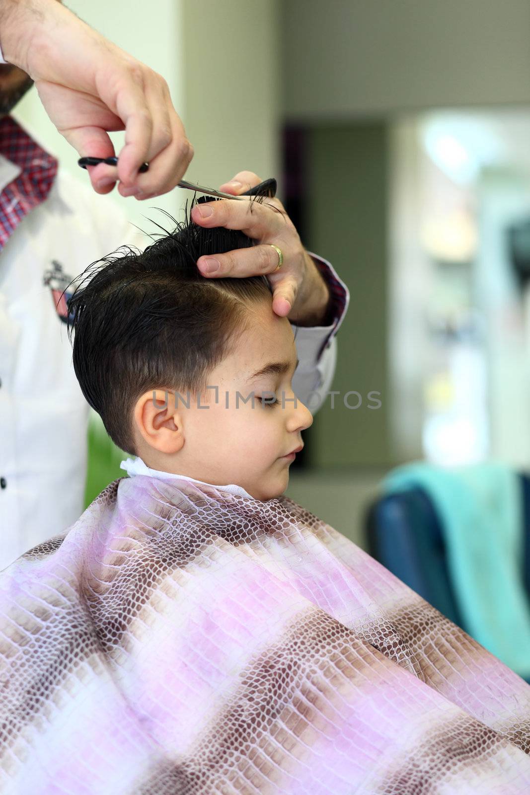 A lovely child in the hairdresser salon cutting his hair