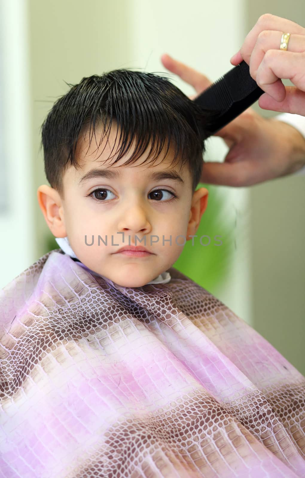 A lovely child in the hairdresser salon cutting his hair