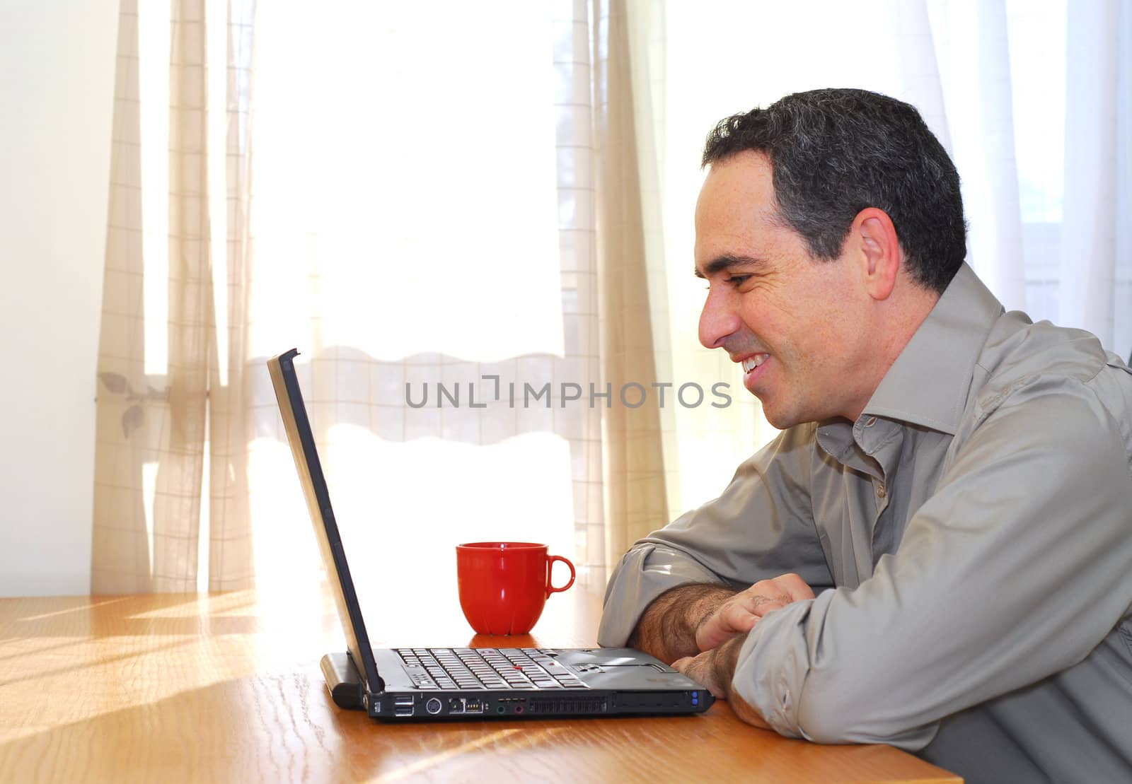 Man sitting at his desk with a laptop looking happy