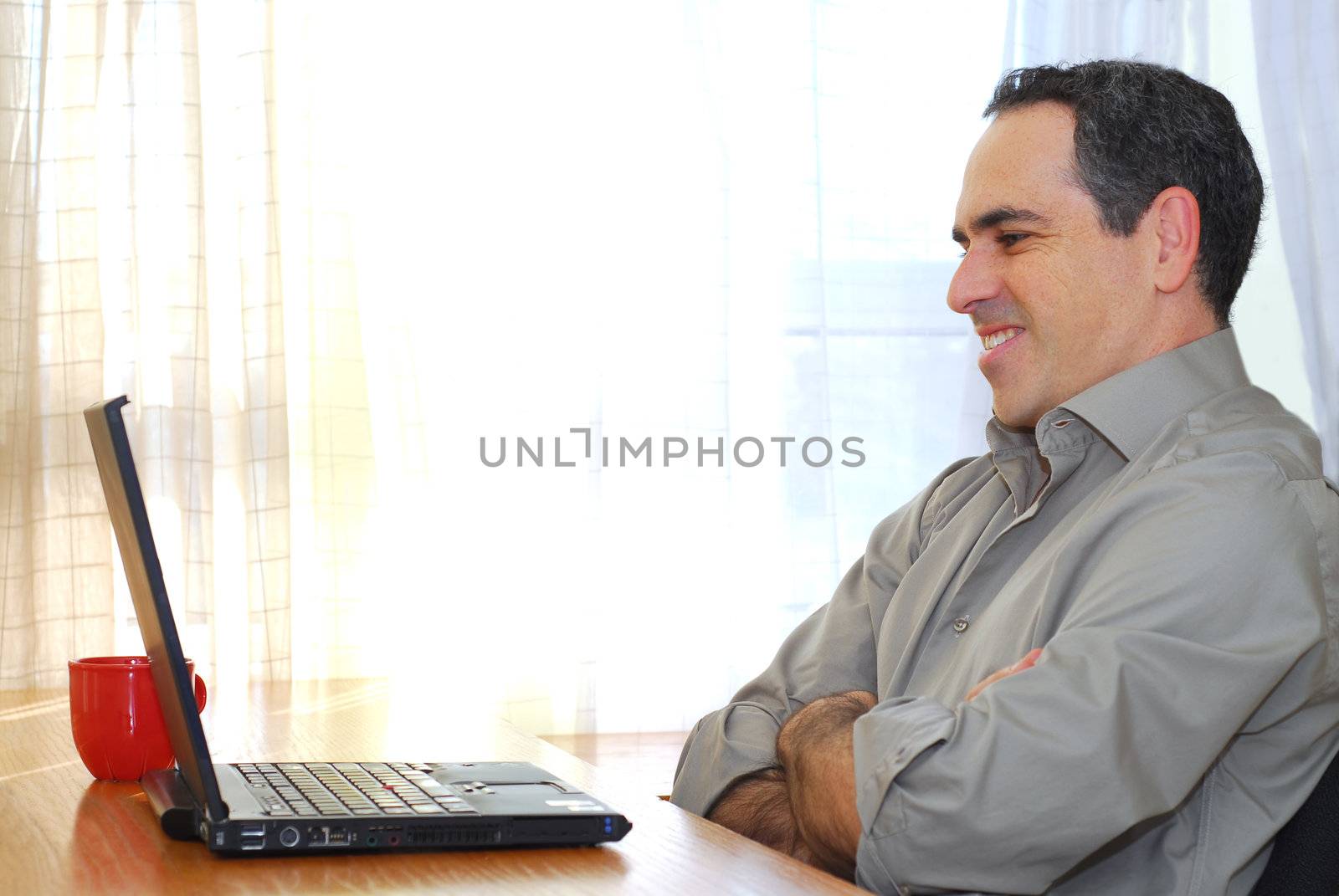 Man sitting at his desk with a laptop looking happy