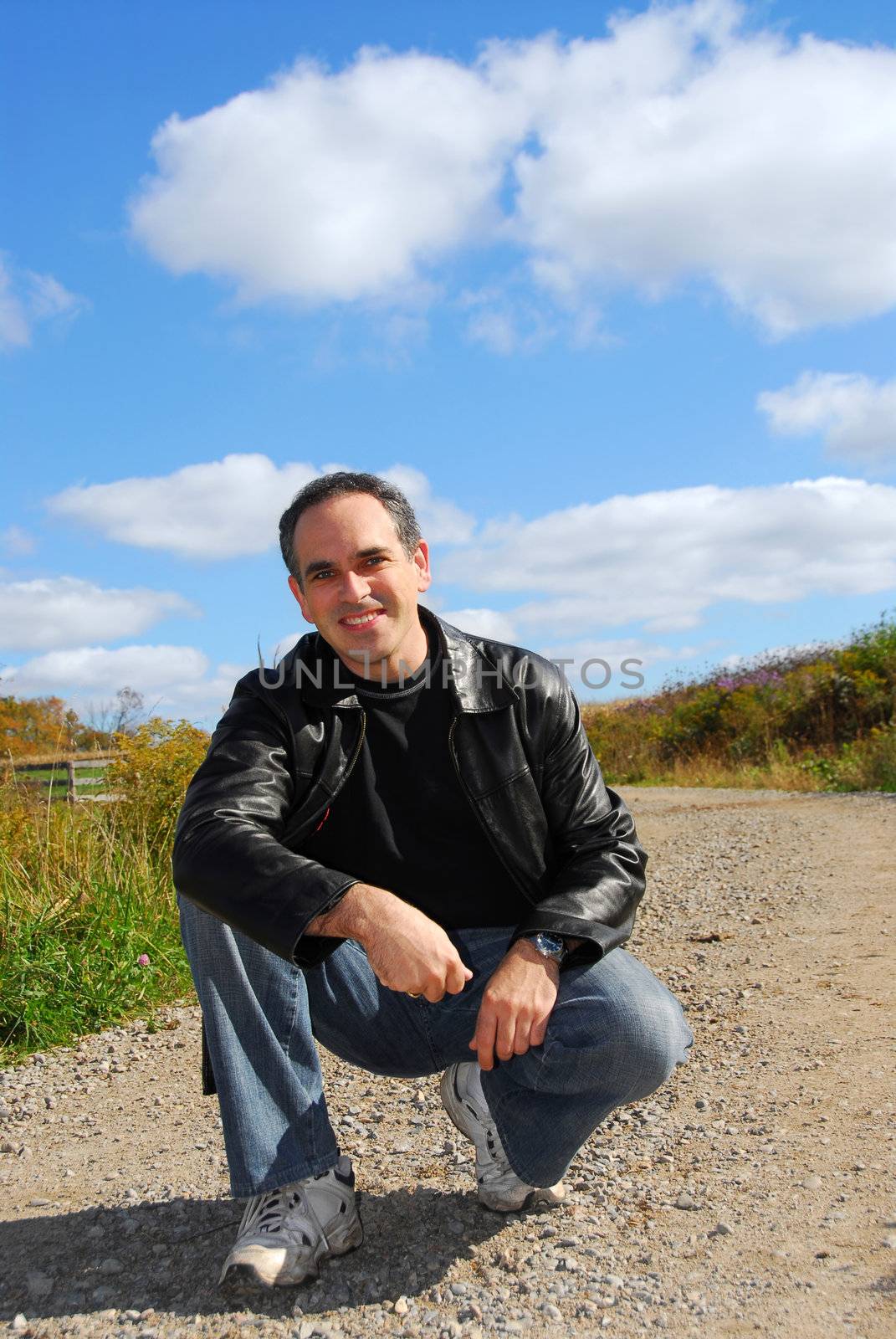 Smiling man sitting on a country road