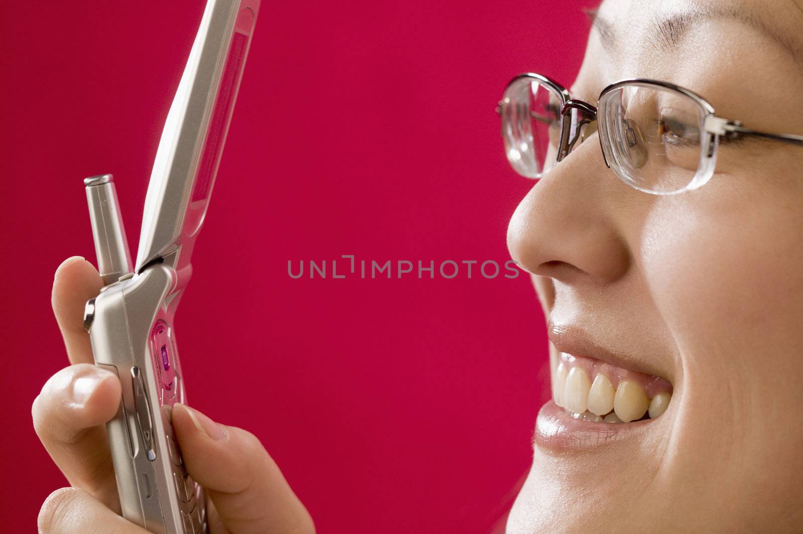 Pretty smiling young Asian woman texting with a cell phone