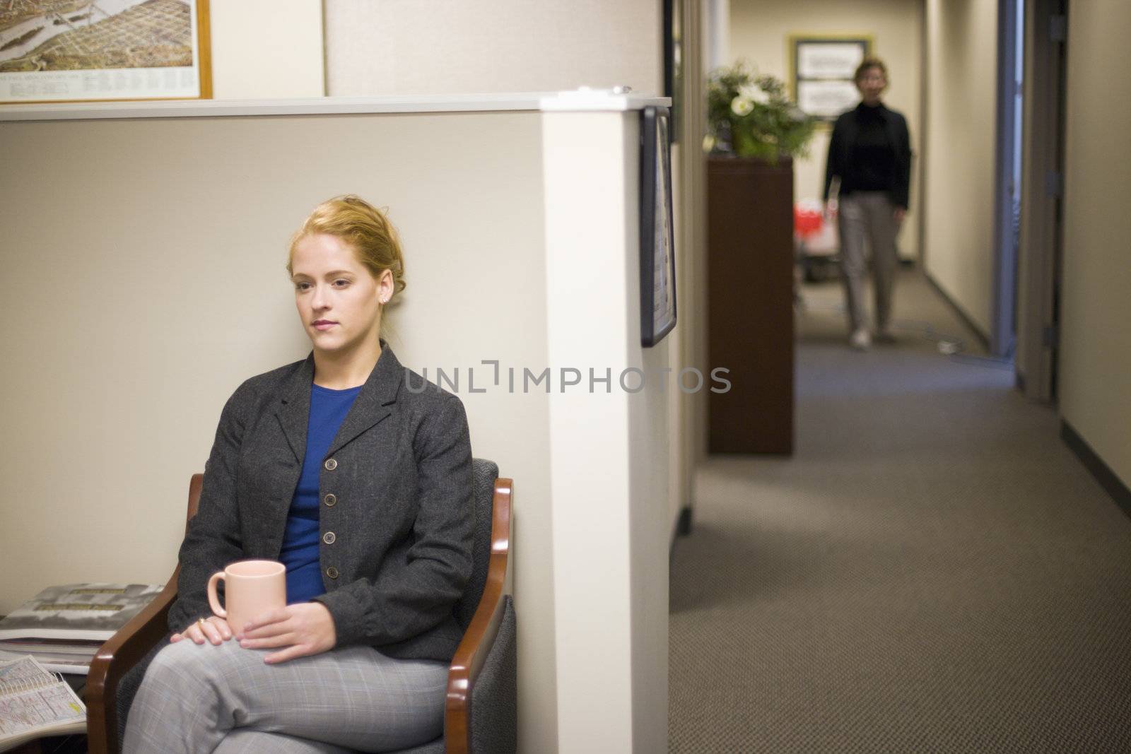 Young woman waiting in office lobby holding coffee cup