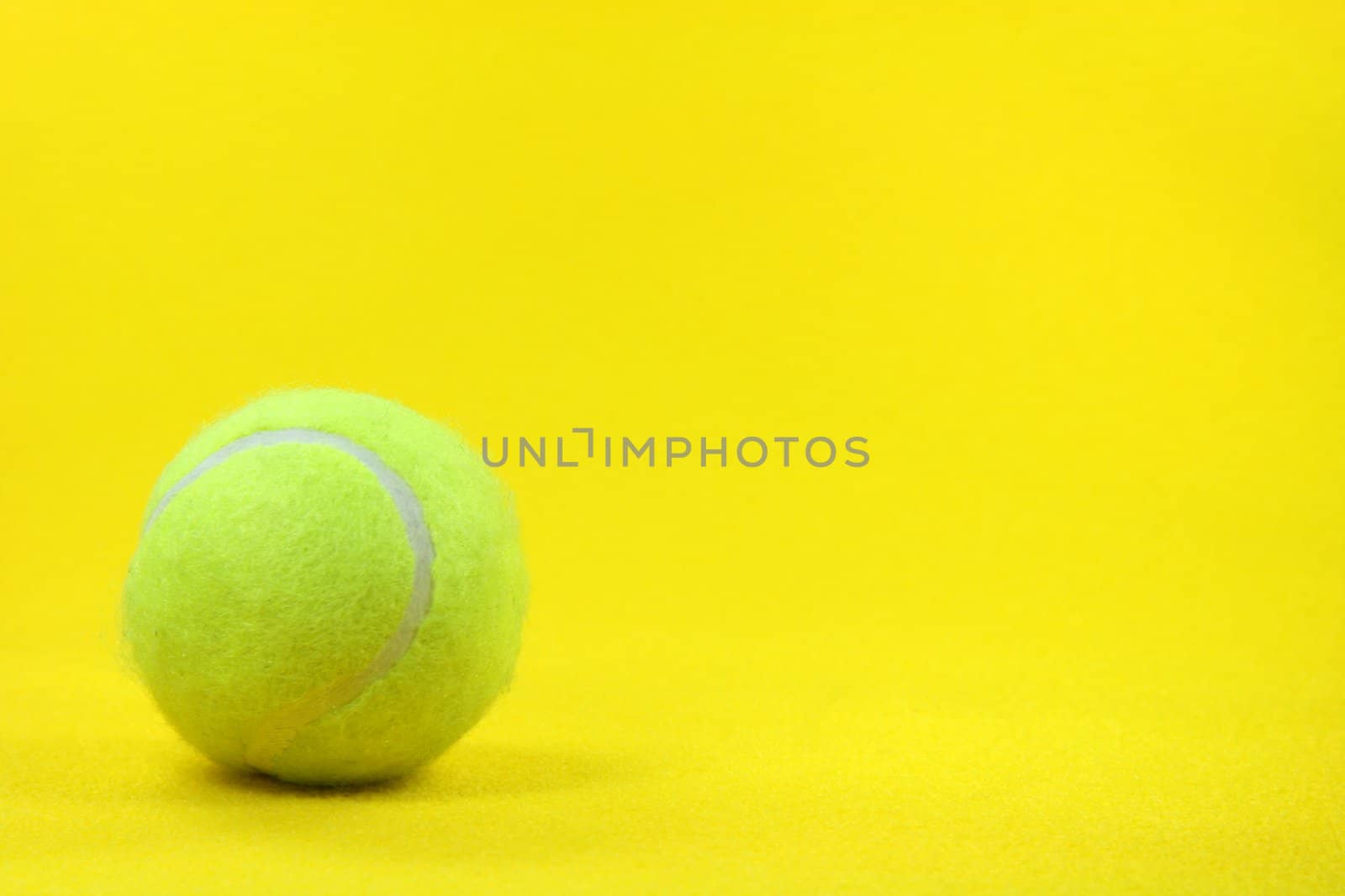 one yellow tennis ball in the left side with yellow background sports concepts
