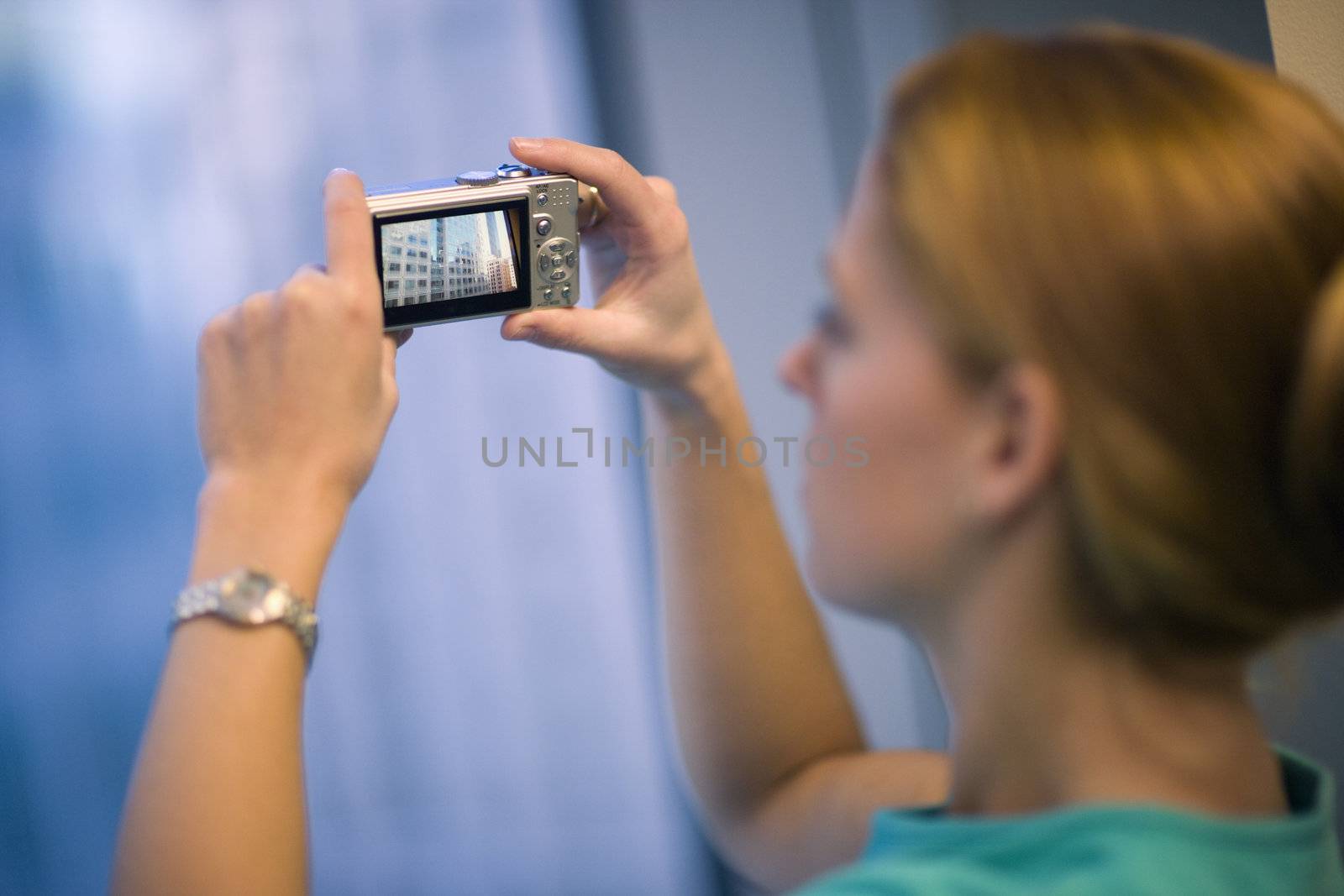 Young woman taking photo of buildings with digital camera