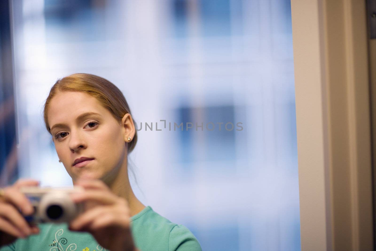 Serious young woman taking pictures with digital camera
