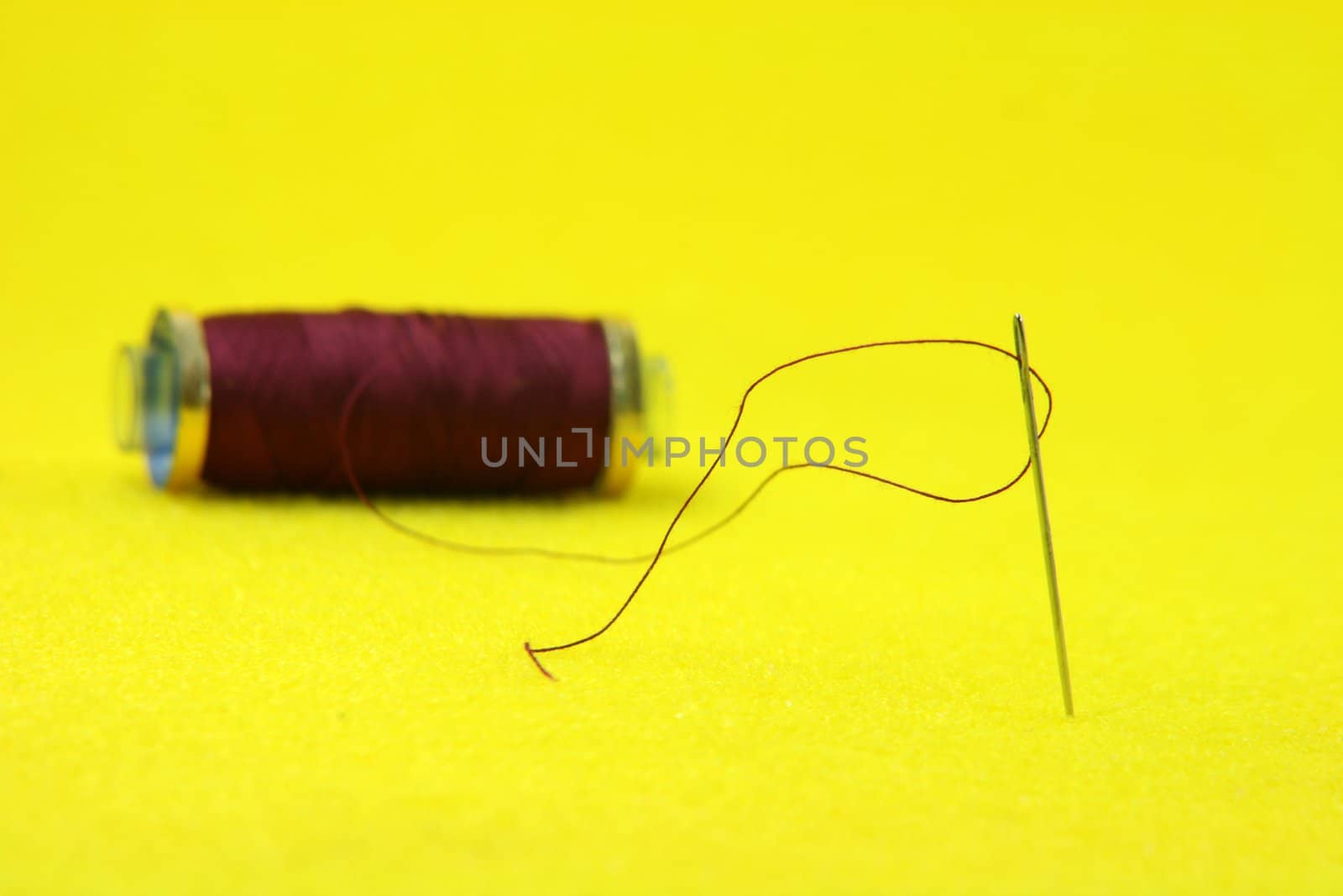 needle with redish string in yellow background sewing handcrafted concepts